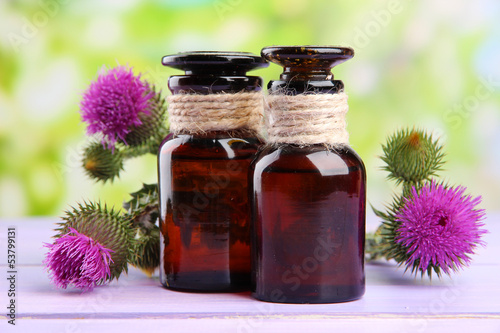 Medicine bottles with thistle flowers on nature background