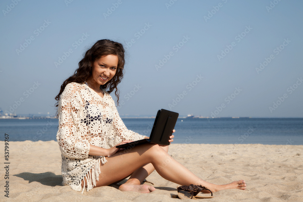 Beautiful girl working on the tablet at the beach