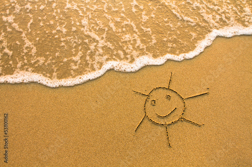 A sun drawn in the sand of a beach. photo