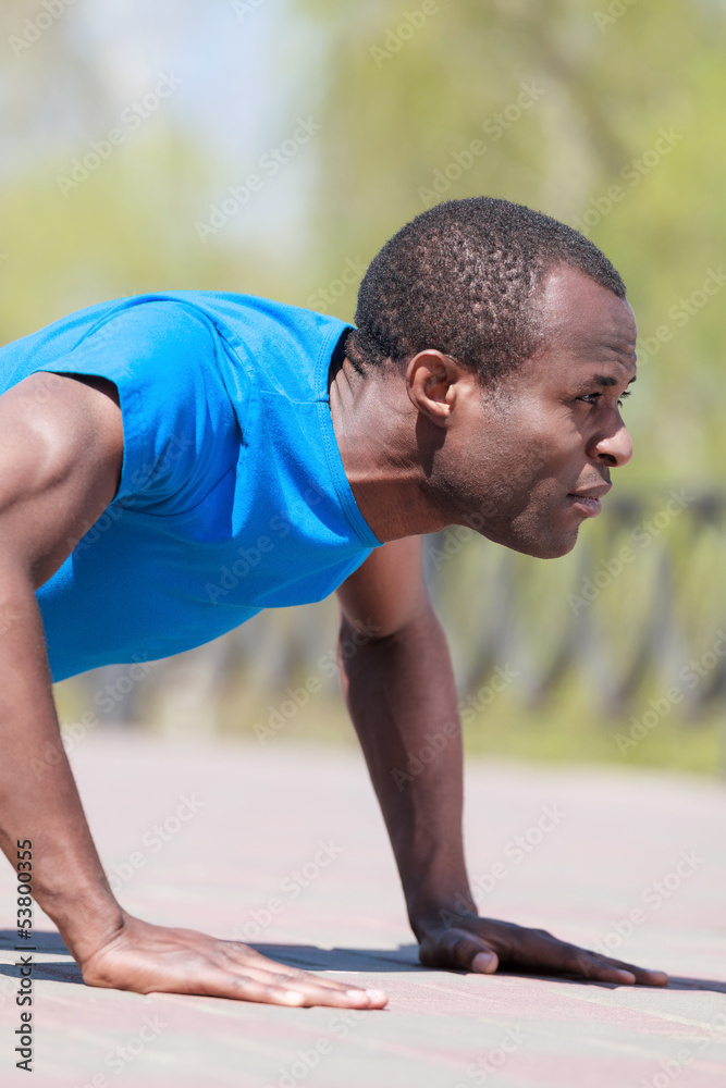 Fototapeta premium Doing push-ups. Side view of young african men doing push-ups