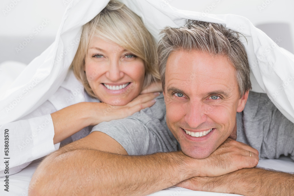 Couple smiling under the covers Couple smiling under the covers