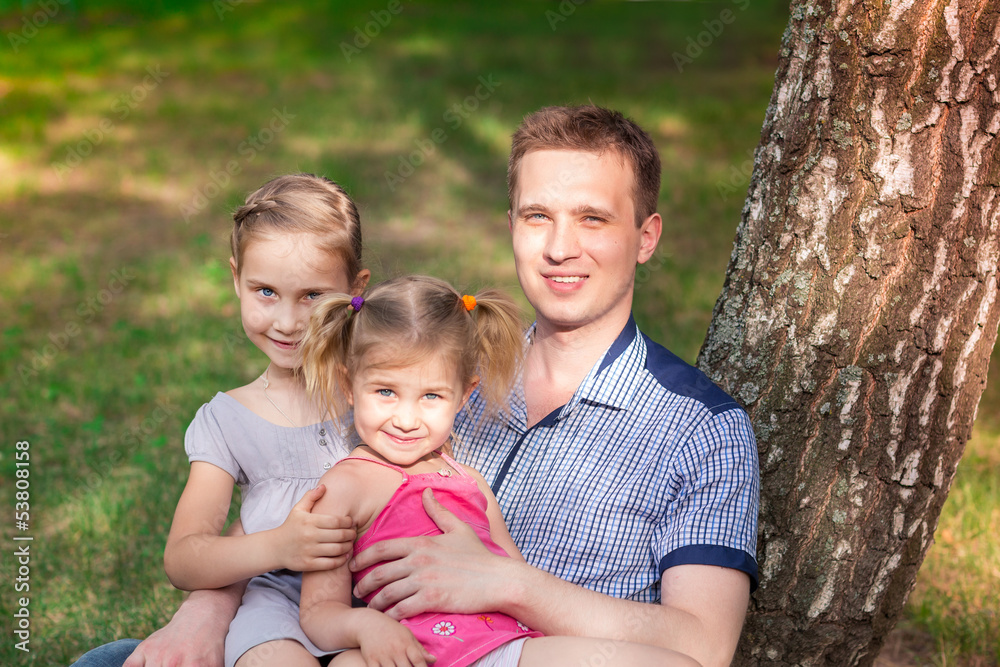 Happy father with daughters playing in the park Happy father with daughters playing in the park