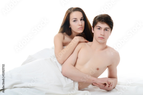 Beautiful pair lays in bed on white