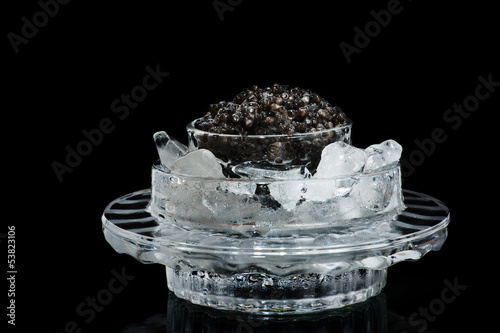 Black caviar in ice on a black photo