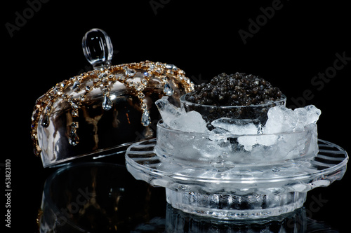 Black caviar in ice on a black isolated studio photo