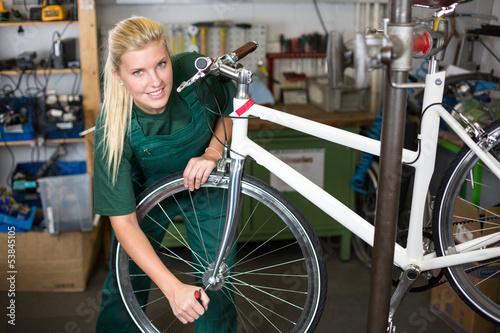 Bicycle mechanic repairing wheel on bike in a workshop