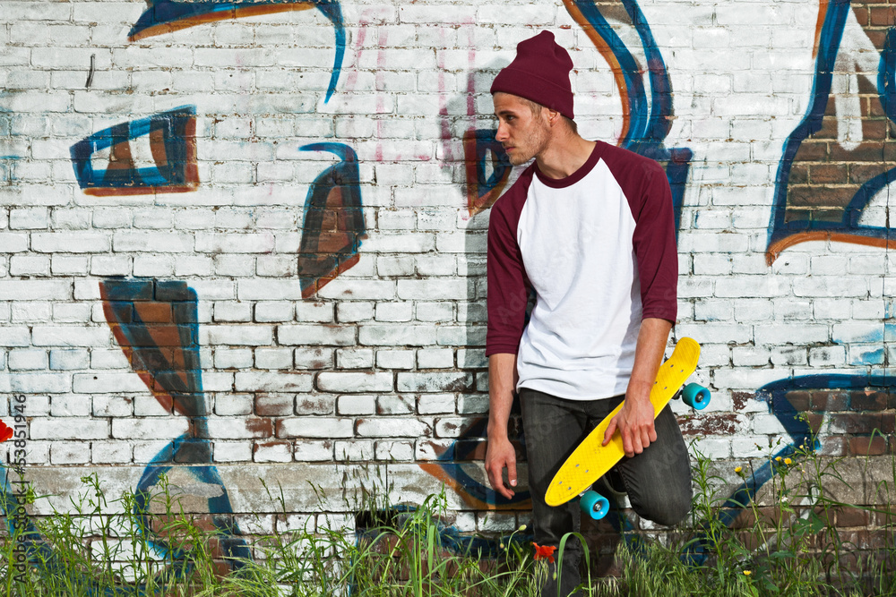 Obraz premium Hip cool urban fashion skateboarder with woolen hat posing in fr