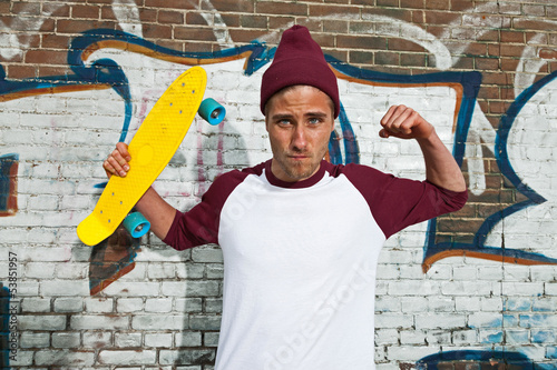 Crazy expressive skateboarder with woolen cap in front of graffi photo