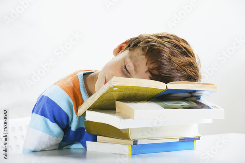 Tired schoolboy studying in home.