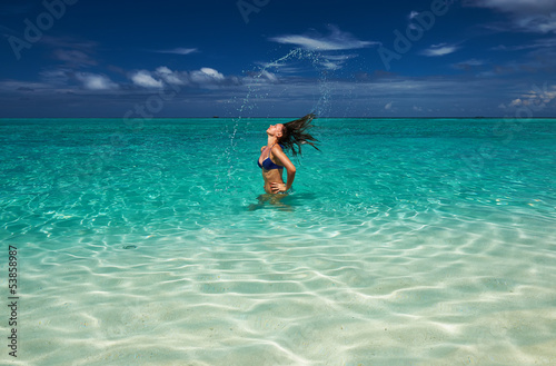 Woman splashing water with hair in the ocean
