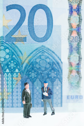 Miniature men strolling with twenty Euro banknote background