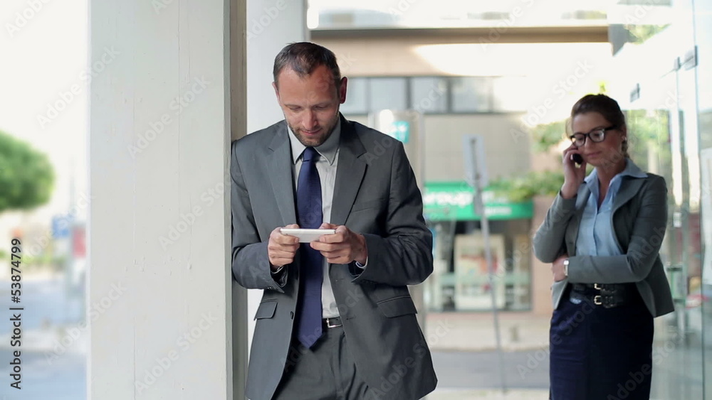 Businessman with smartphone, businesswoman talking on cellphone Businessman with smartphone, businesswoman talking on cellphone