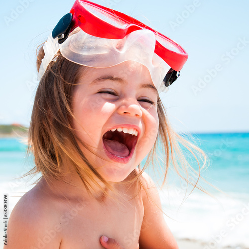 Bambina al mare con maschera che ride