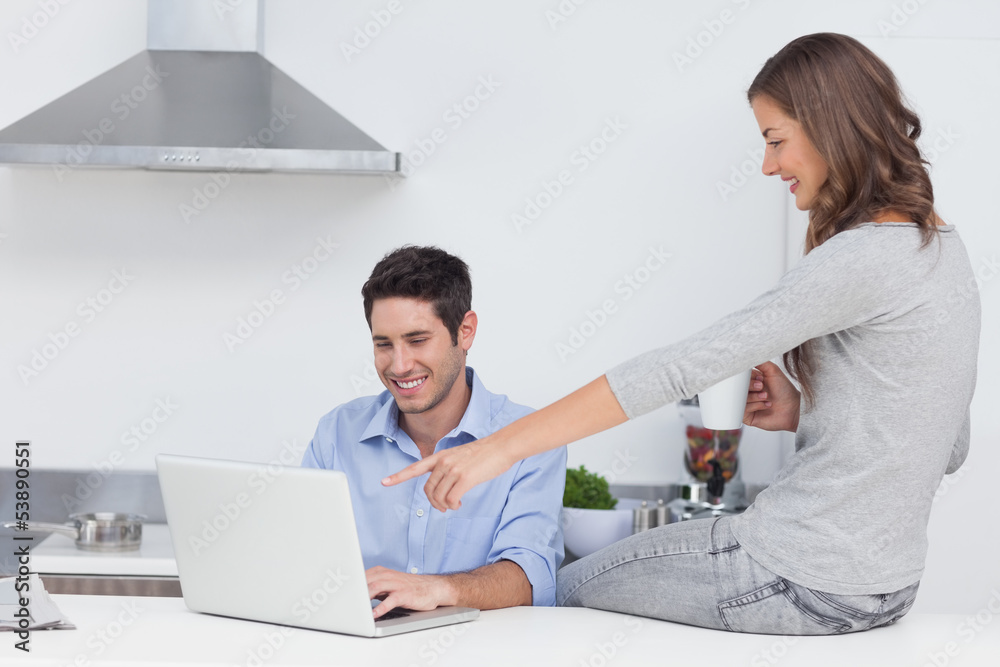 Obraz premium Wife pointing at the laptop of her husband