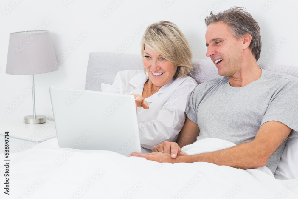 Happy couple using laptop in bed Happy couple using laptop in bed