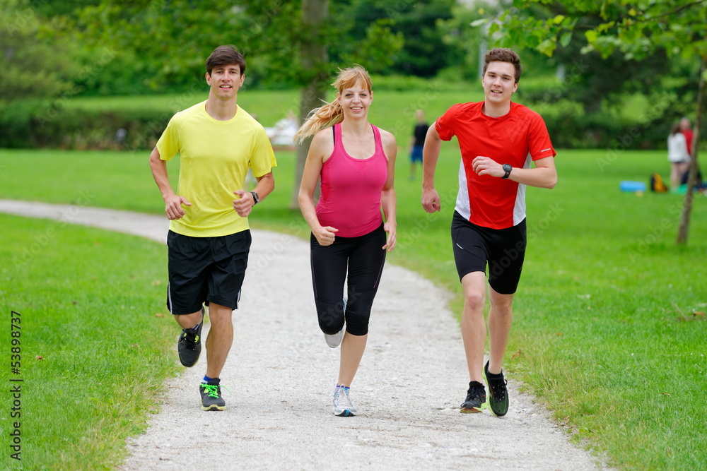 Fototapeta premium Front view of three athletes jogging in the park