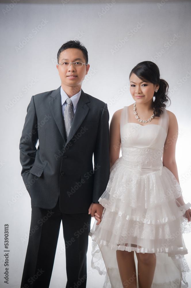 Bride and Groom posing in wedding dress at studio, smiling Bride and Groom posing in wedding dress at studio, smiling