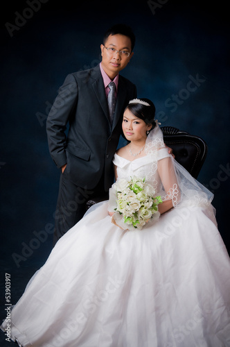 Bride and Groom posing in wedding dress at studio, smiling