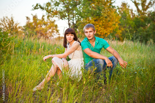 Portrait of young romantic couple sitting in forest enjoying