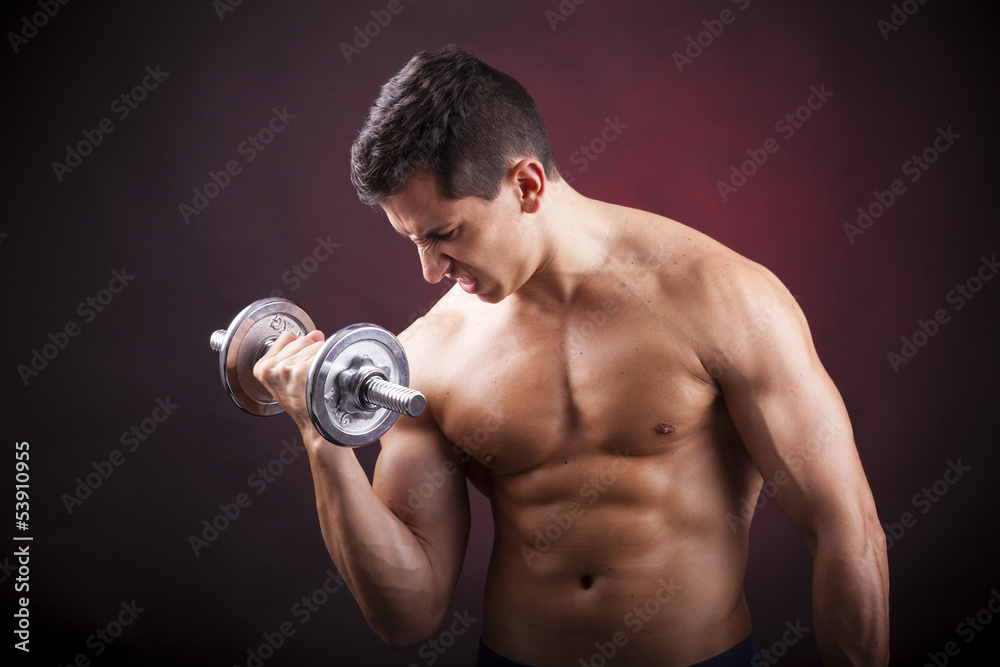 Muscular young man lifting weights on dark background