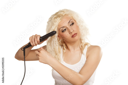 Cute curly blonde thinks while ironing her hair
