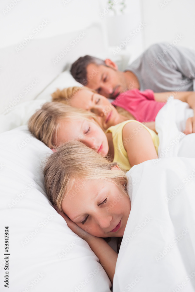 Fototapeta premium Parents sleeping with their twins in bed