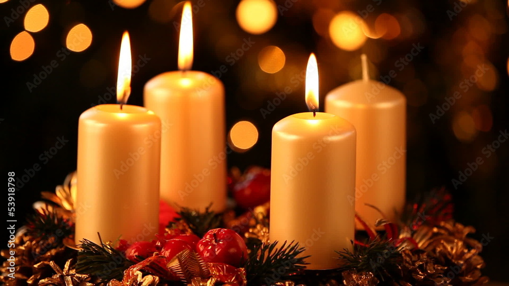 Candles on advent wreath and hand igniting the fourth candle.