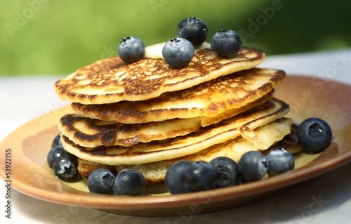Stack of pancakes with blueberries on garden table