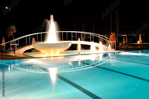 Swimming pool with fountain in night illumination at the luxury