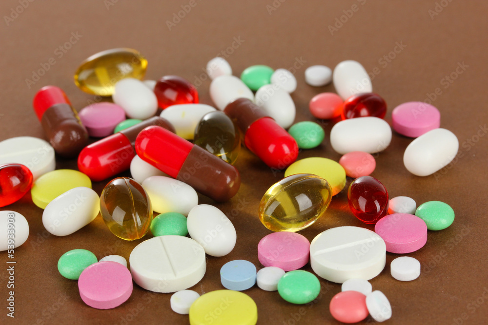 Assortment of pills, tablets and capsules on brown background Assortment of pills, tablets and capsules on brown background