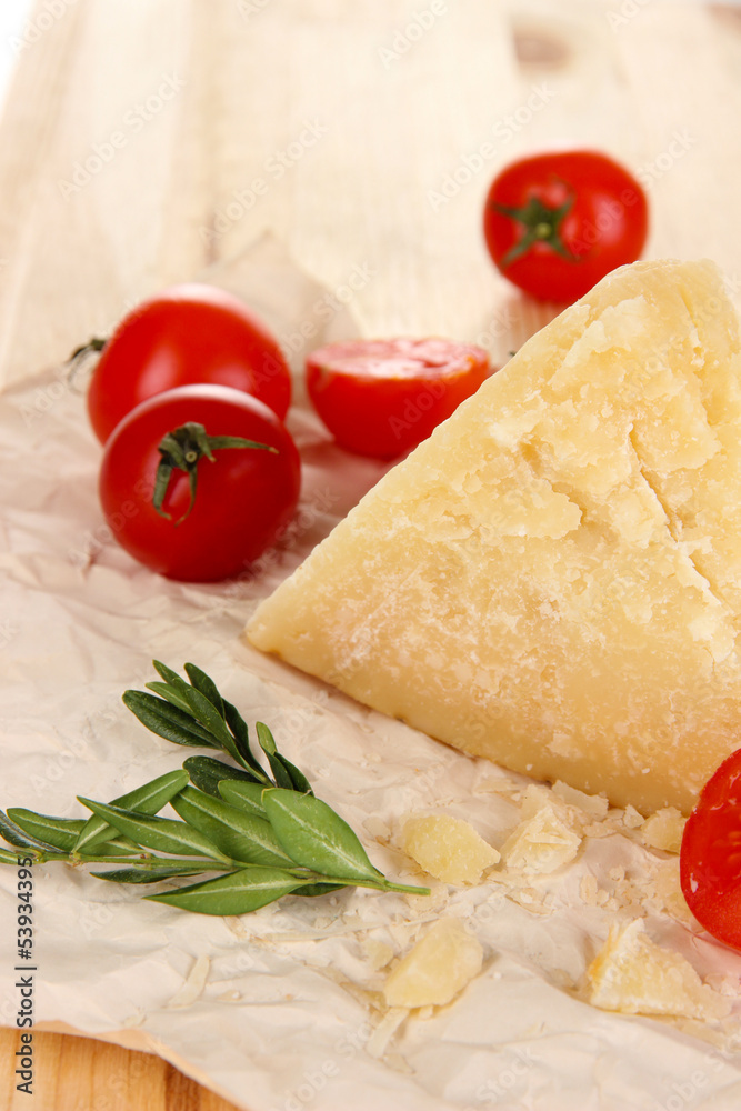 Piece of Parmesan cheese on paper on wooden table close-up