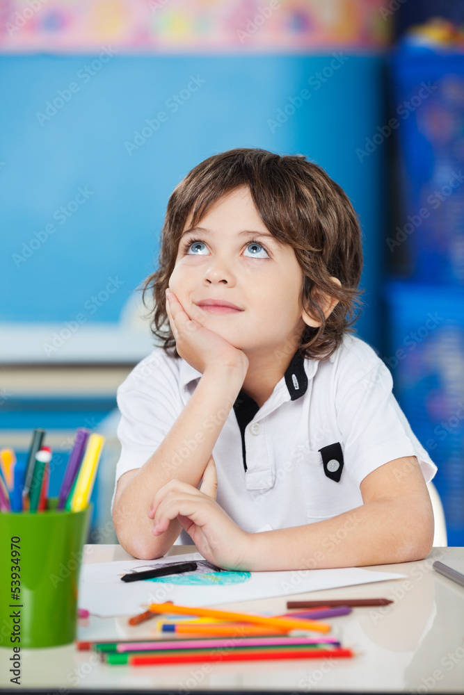 Boy Looking Up While Sitting With Hand On Chin At Desk Boy Looking Up While Sitting With Hand On Chin At Desk
