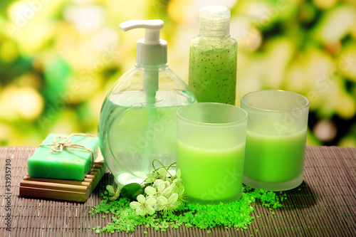 Cosmetics bottles and natural handmade soap on green background