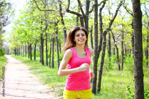 Attractive young woman running in summer park