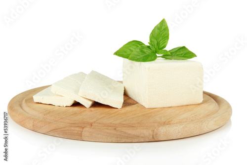 Sheep milk cheese with basil on cutting board, isolated on