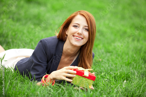 Redhead women wtih gift at green grass.