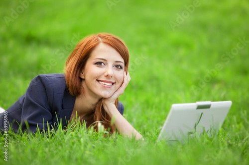 Redhead girl at green grass with notebook