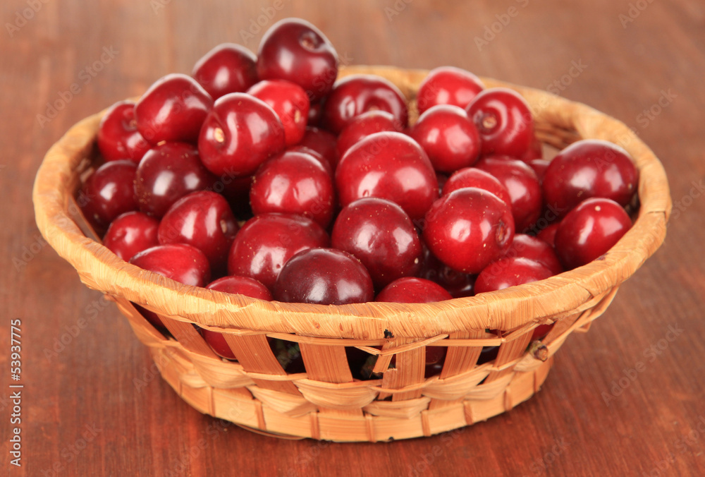 Cherry berries in wicker basket on wooden table close-up Cherry berries in wicker basket on wooden table close-up