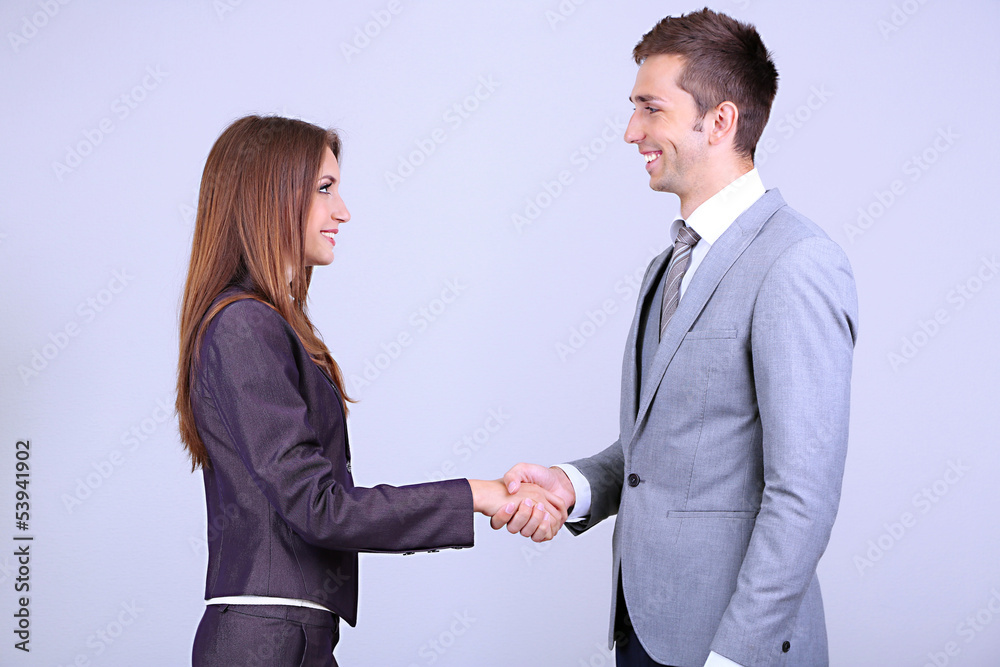 Business colleagues shaking hands on grey background Business colleagues shaking hands on grey background