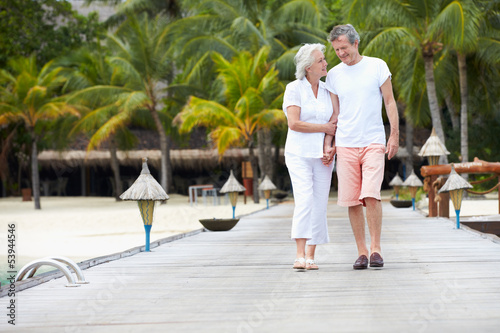 Senior Couple Walking On Wooden Jetty