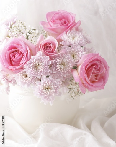 Pink and white flowers in a vase with white decorative fabric