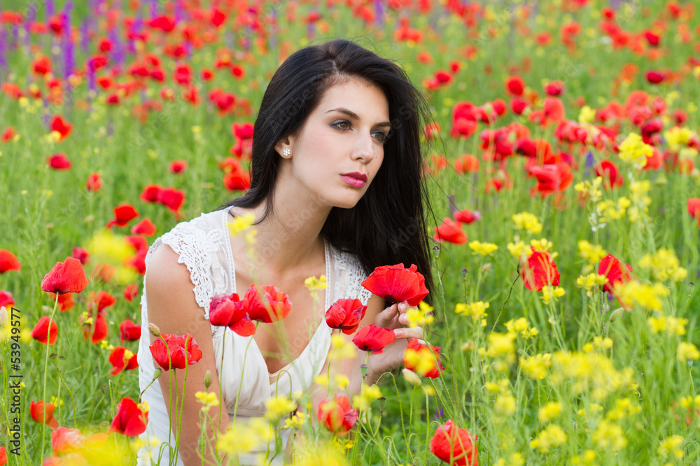 Naklejka premium beautiful girl with long hair sitting in the poppy field