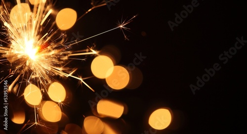 Close-up of sparkler on Christmas lights background photo