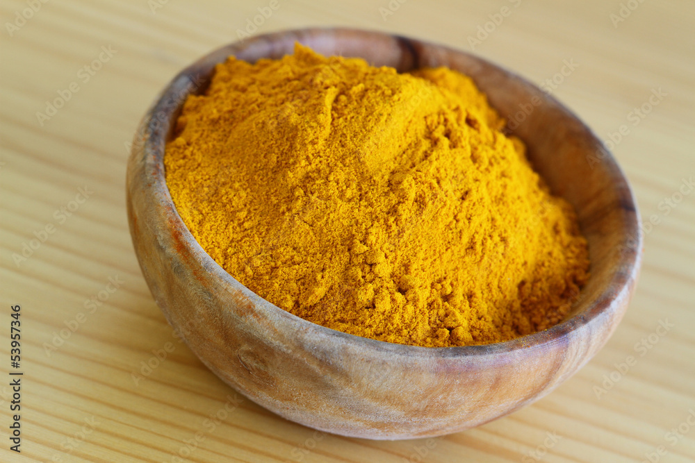 Tumeric powder in wooden bowl, close up Tumeric powder in wooden bowl, close up