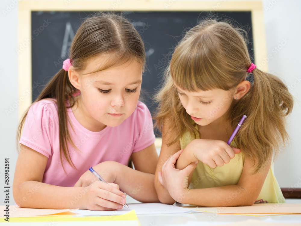 Little girls are writing using a pen Little girls are writing using a pen