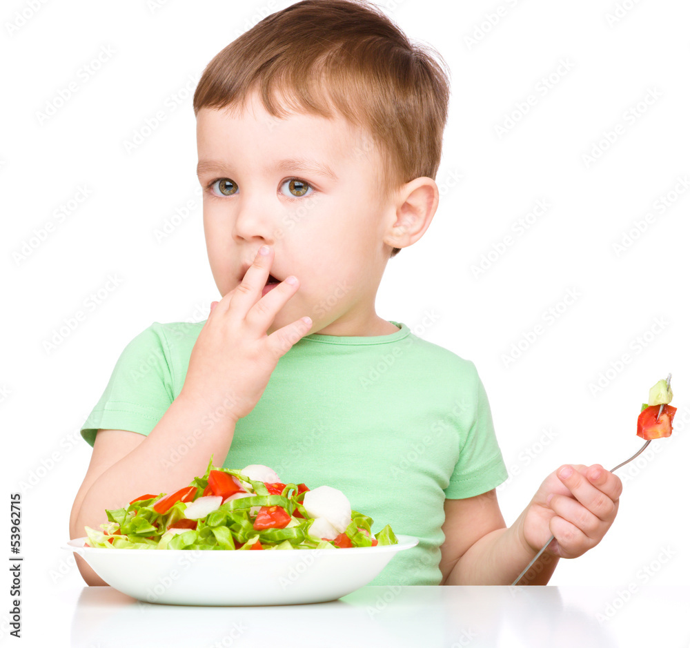 Cute little boy is eating vegetable salad Cute little boy is eating vegetable salad
