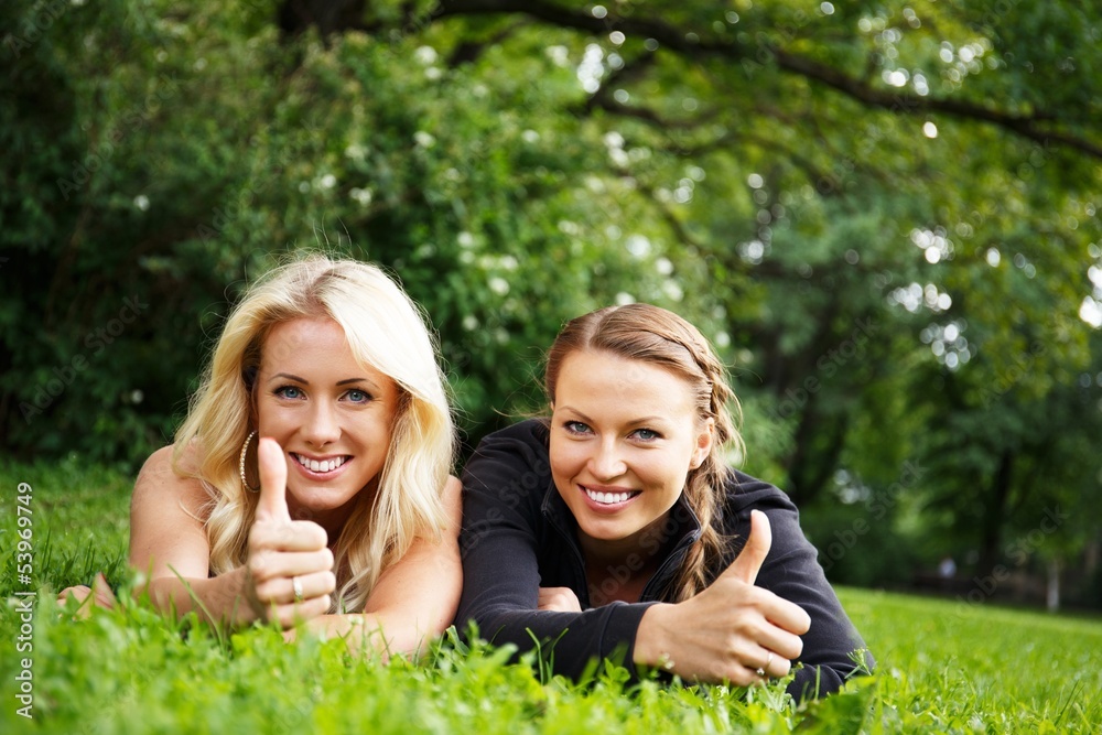 Two smiling athletic girls sitting on a grass in a park Two smiling athletic girls sitting on a grass in a park