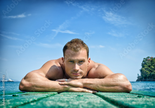 Muscular young man resting his chin on his hands