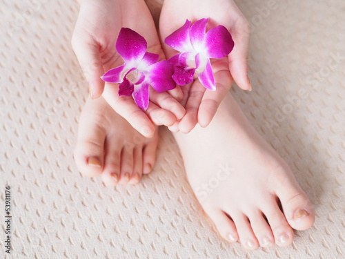 Young woman's hands, feet  and orchid flower