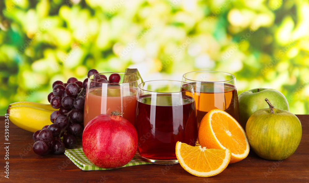 Glasses of fresh juice on table on bright background Glasses of fresh juice on table on bright background